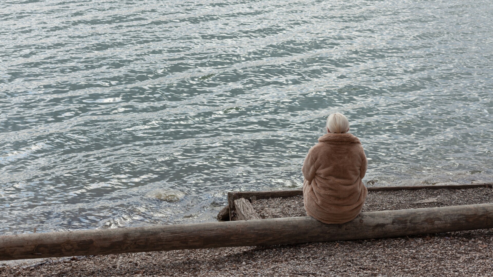 A woman sitting by the water alone showing widow resilience